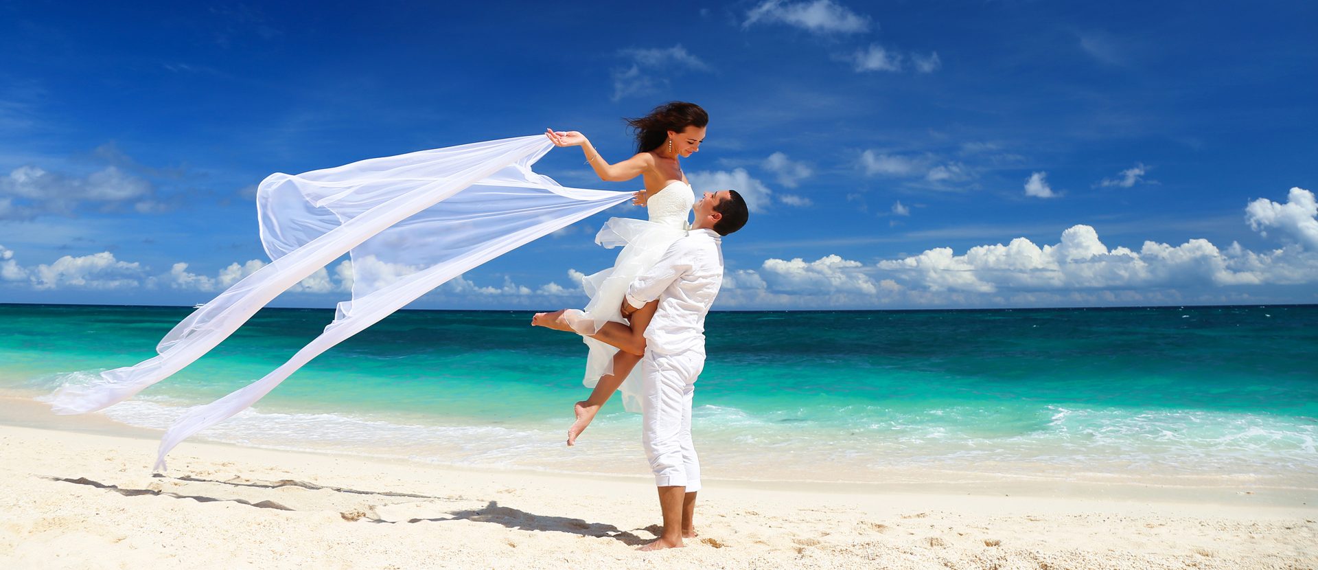Couple wearing white on beach-destination wedding - panorama